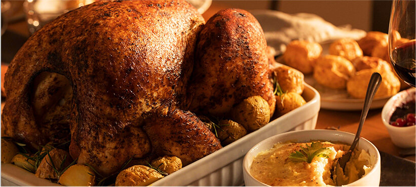 Thanksgiving meal: turkey on a bed of potatoes, surrounded by thanksgiving foods.
